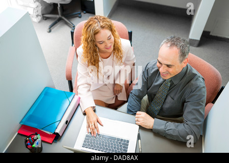 L uomo e la donna seduta alla scrivania con computer in ufficio Foto Stock