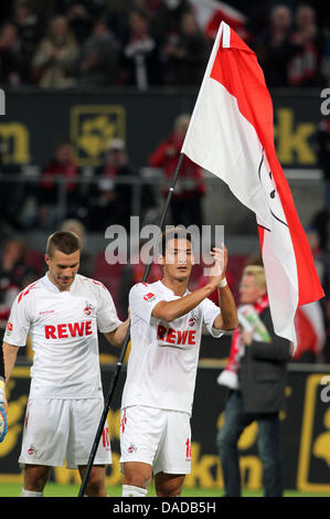 Koeln Marcatore a doppia Lukas Podolski (L) sventola una bandiera con la colonia stemma della città mentre Mato Jajajo applaude i tifosi dopo la Bundesliga partita di calcio tra 1. FC Koeln e Hannover 96 al Rheinenergie Stadium di Colonia, Germania, 16 ottobre 2011. Koeln vince 2-0. Foto: ROLAND WEIHRAUCH (ATTENZIONE: embargo condizioni! Il DFL permette l'ulteriore utilizzazione del pict Foto Stock