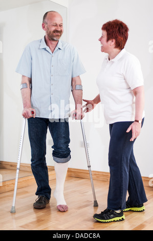 Uomo con le stampelle parlando di donna Foto Stock