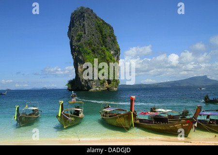 Coda lunga imbarcazioni presso la spiaggia di fronte all imponente roccia carsica formazione, Thailandia, Krabi, Laem Phra Nang Foto Stock