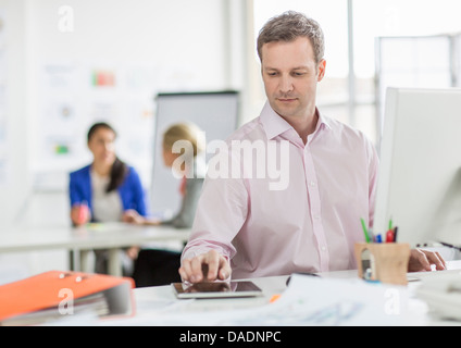 Imprenditore maturo con tavoletta digitale alla scrivania in ufficio Foto Stock