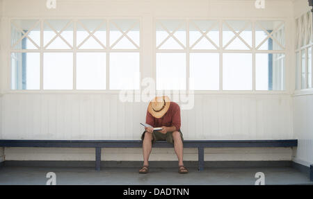 Aberystwyth, Wales, Regno Unito. 11 luglio 2013. - Le persone godono il persistere di sole caldo luglio meteo al mare in questo west wales resort. Un uomo prende di ripararsi dal sole e legge il suo libro all'ombra. Le temperature hanno raggiunto un picco a metà pomeriggio a 24 gradi centigradi (75 gradi Fahrenheit) Photo credit: keith morris/Alamy Live News Foto Stock