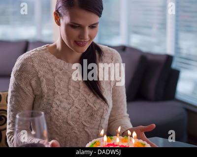 Giovane donna che guarda la torta di compleanno Foto Stock