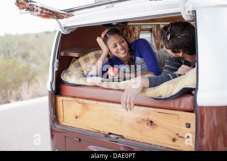 Giovane giacente insieme nel retro del camper, sorridente Foto Stock