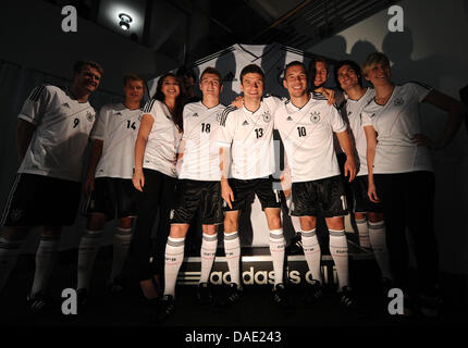 Nazionale tedesco di giocatori di calcio Andre Schuerrle (L-R), Mats Hummels, Lukas Podolski, Thomas Mueller, Per Mertesacker, Toni Kroos e Holger Badstuber posano con due hostess pongono durante la presentazione del nuovo Euro 2012 maglie presso una concessionaria auto ad Amburgo, Germania, 09 novembre 2011.. La selezione tedesca giocherà in Ucraina in un test match in Kiew su 11 Novembre 2011 e ne Foto Stock