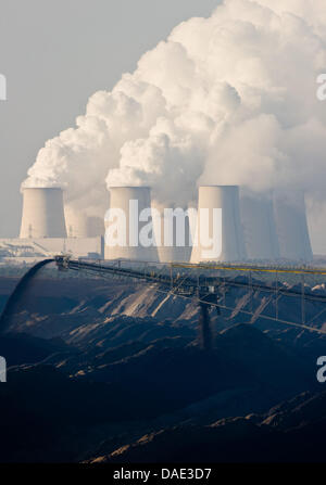 Il marrone fumo centrali a carbone vegetale di Vattenfall AG power company è visto dietro un nastro trasportatore ponte del carbone marrone striscia in miniera Jaenschwalde, Germania, 11 novembre 2011. In vista della conferenza mondiale sul clima entro la fine di novembre a Durban, Sud Africa, testimoni di cambiamento climatico da paesi in via di sviluppo hanno visitato la Vattenfall brown centrali a carbone vegetale in Jaenschwal Foto Stock