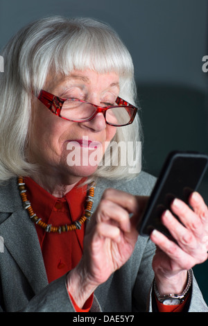 Senior donna utilizza lo smartphone Foto Stock