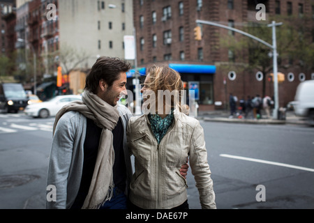 Coppia sorridente camminando insieme lungo una strada di città Foto Stock