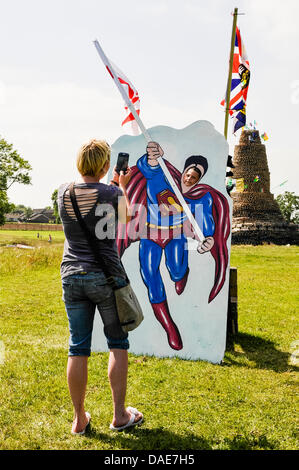 Newtownabbey, Irlanda del Nord. 11 luglio 2013. Una madre si prende una fotografia di suo figlio attraverso un intaglio di Superman board tenendo una bandiera unionista ad un protestante falò. Credito: Stephen Barnes/Alamy Live News Foto Stock