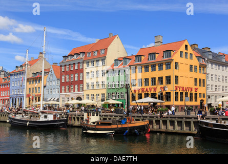 Vecchie barche di legno ormeggiate sul canal da colorati del xvii secolo edifici sul lungomare occupato con le persone nella città vecchia. Nyhavn Copenhagen DANIMARCA Foto Stock