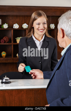 Donna sorridente receptionist in hotel saluto un uomo anziano Foto Stock