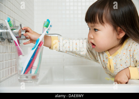 Close up girl toddler ruotando il lavandino del bagno rubinetti Foto Stock