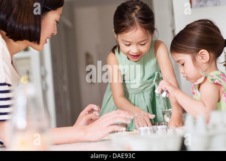 Madre e giovani figlie rendendo la pasticceria Foto Stock