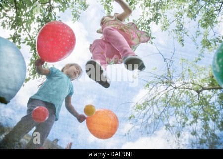 Le ragazze di saltare sul trampolino da giardino con palloncini Foto Stock