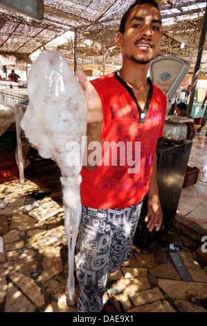 Fish monger al mercato del pesce che mostra con orgoglio il calamaro, Egitto, Hurghada Foto Stock