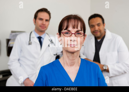 Medico senior con i colleghi in background, ritratto Foto Stock