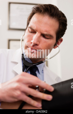 Metà adulto medico utilizzando uno stetoscopio e bracciale per la misurazione della pressione sanguigna del paziente, close up Foto Stock