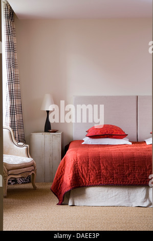 Di seta rossa su quilt letto doppio con il grigio testata rivestita in camera da letto moderna con lampada nero su grigio verniciato armadio al posto letto Foto Stock