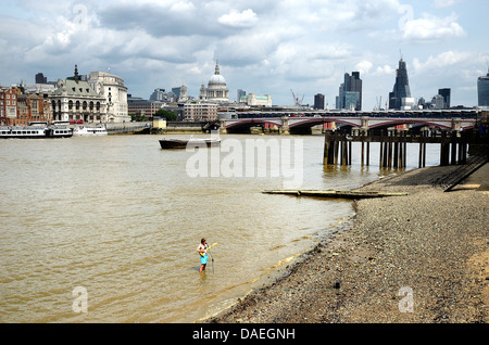 Busker in piedi nel fiume Tamigi sulla banca del sud con la città di Londra in background, England Regno Unito Foto Stock