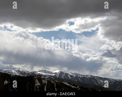 Luminose back lit nuvole sulla montagna innevata tops Foto Stock