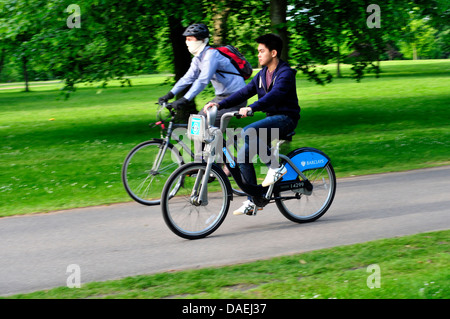 Due uomini in bicicletta nei giardini di Kensington, London, Regno Unito Foto Stock