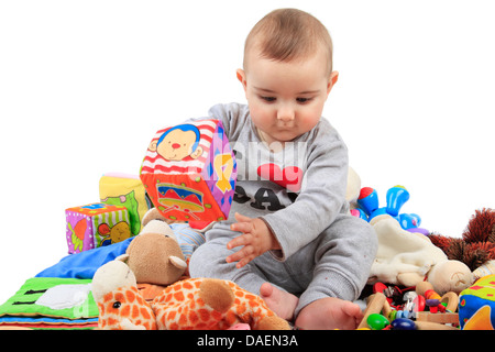 Baby sitting in un mucchio di giocattoli Foto Stock