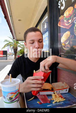 Un 18-anno-vecchio maschio mangia fast food. Foto Stock