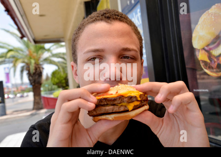 Un 18-anno-vecchio maschio mangia fast food. Foto Stock