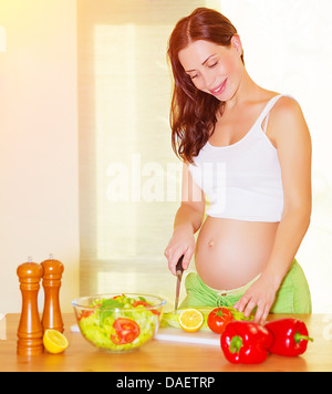 Bella donna incinta insalata di cottura sulla cucina a casa, nutrizione sana, tagliare le verdure Foto Stock