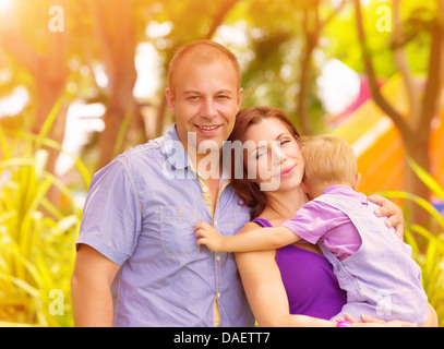 Closeup ritratto di famiglia felice nel parco, madre portano little baby boy, i genitori con bambini carino godendo di giorno caldo e soleggiato Foto Stock