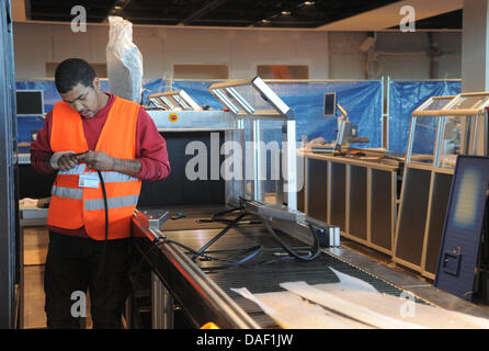 Un elettricista opere su un security check-point presso la nuova BER aeroporto di Schoenefeld, Germania, 25 novembre 2011. Al momento, TÜV è che approva la sicurezza dello stato tecnico dell'jetways. Quando l'aeroporto apre il 3 giugno 2012, sarà in grado di gestire circa 27 milioni di passeggeri ogni anno a Berlino. Foto: BERND SETTNIK Foto Stock