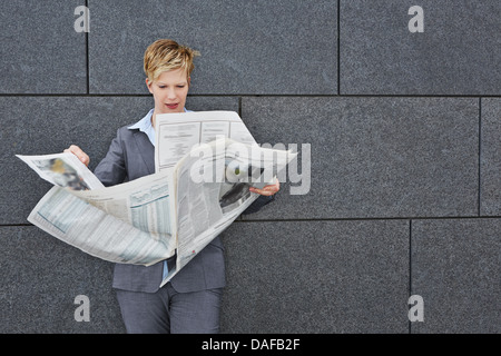 Business donna la lettura di un quotidiano in tempo ventoso all'aperto Foto Stock