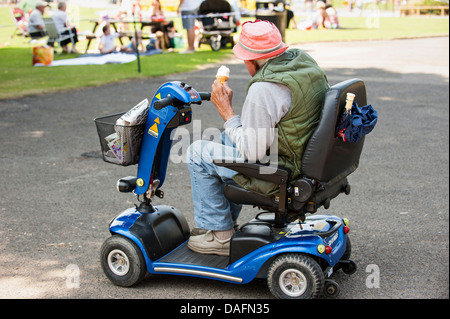 Uomo anziano sulla mobilità scooter orologi giovani divertirsi Foto Stock