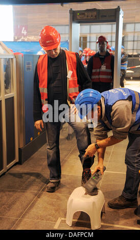 I passeggeri di test provano un controllo di sicurezza durante una prova di eseguire in futuro Berlin-Brandenburg, aeroporto di Schoenefeld, Germania, 08 dicembre 2011. Dal check-in attraverso i controlli di sicurezza, i dipendenti della compagnia aerea, i funzionari di polizia e i dipendenti Globeground assistere alla prova al futuro aeroporto di BER. Non appena il Willy-Brandt-Airport sarà aperta il 03 giugno 2012, 27 milioni di passeggeri per voi Foto Stock