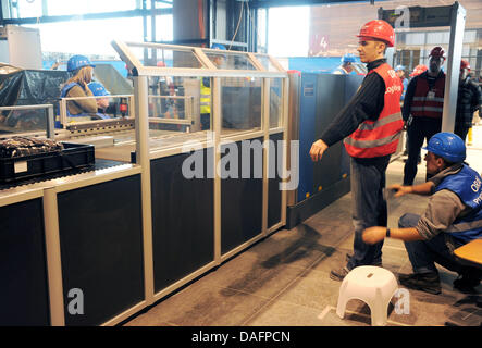 I passeggeri di test provano un controllo di sicurezza durante una prova di eseguire in futuro Berlin-Brandenburg, aeroporto di Schoenefeld, Germania, 08 dicembre 2011. Dal check-in attraverso i controlli di sicurezza, i dipendenti della compagnia aerea, i funzionari di polizia e i dipendenti Globeground assistere alla prova al futuro aeroporto di BER. Non appena il Willy-Brandt-Airport sarà aperta il 03 giugno 2012, 27 milioni di passeggeri per voi Foto Stock