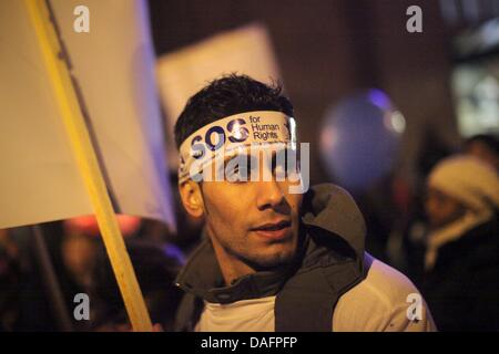 Un uomo che indossa una 'SOS per i diritti dell'uomo' archetto si unisce a una manifestazione di protesta per un diritto di residenza per gli stranieri assemblati di fronte la stazione centrale di Wiesbaden, Germania, 07 dicembre 2011. Organizzazione Sociale e i partiti politici hanno chiamato per le nuove politiche per il diritto di residenza permanente prima della conferenza dei ministri dell'interno. Secondo la polizia, circa 150 persone Foto Stock