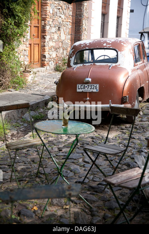 Scena di strada con cafe tabelle e vintage Hilman auto in Colonia del Sacramento, Uruguay Foto Stock