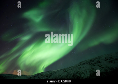 Aurora vortice in parte anteriore del cielo stellato sopra coperta di neve pendii montani, Norvegia, Troms, Kvaloea, Kattfjordeidet Foto Stock