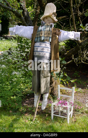 Rustico spaventapasseri vestito con un abito vecchio con dipinti di bianco sedia per il bambino nel giardino di campagna Foto Stock