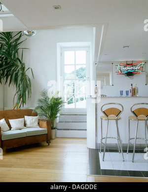 Il pavimento in legno e alte houseplants accanto al divano nella moderna cucina soggiorno in cappella convertito Foto Stock