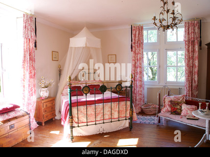 Voile bianco zanzariera sopra il letto in ottone con Toile de Jouy coperchio in angolo del paese francese camera con Toile de Jouy oscuranti Foto Stock