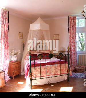 Voile bianco zanzariera sopra il letto in ottone con Toile de Jouy coperchio in angolo del paese francese camera con Toile de Jouy oscuranti Foto Stock