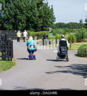 Elderley coppia in pensione sulla mobilità Scooter e sedie a rotelle Foto Stock