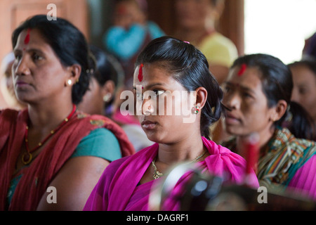 Tharu donne in un incontro di comunità hall. Bardia. Zona di Bheri, Regione Mid-Western, Terai. Il Nepal. Nota abito, tilaka sul fronte. Foto Stock