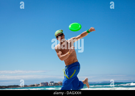 Attraente uomo giocando frisby sulla spiaggia in estate sport fitness jump Foto Stock