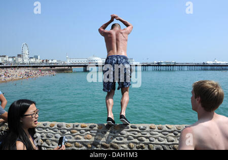 Brighton Regno Unito 13 luglio 2013 - I giovani uomini che saltava o tombstoning come è noto da un groyne in mare sulla spiaggia di Brighton oggi come l'ondata di caldo ha continuato con esso dovrebbe raggiungere le temperature più calde dell'anno finora. Polizia e pattuglie di spiaggia sempre in guardia contro i pericoli di tombstoning come loro sono stati molti incidenti e lesioni negli ultimi anni fotografia scattata da Simon Dack/Alamy Live News Foto Stock