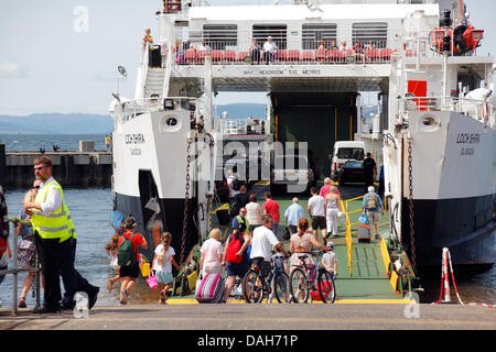 Largs, Nord Ayrshire, Scozia, Regno Unito, Sabato, 13 luglio, 2013. I passeggeri sotto il sole caldo salendo a bordo di un traghetto Caledonian Macbrayne per viaggiare dalla città di Largs all'isola di Great Cumbrae nel Firth di Clyde il primo sabato della tradizionale vacanza della fiera di Glasgow Foto Stock