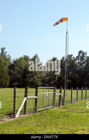 Recintato cancello di ingresso protegge atterraggio rurali striscia servendo il Cedar Key, Florida area. Un vento calza è montata su un montante metallico. Foto Stock