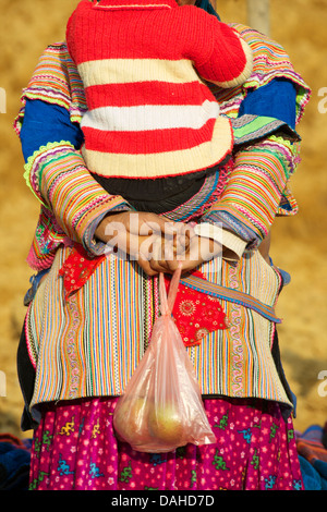 Dettaglio del fiore donna Hmong distintivo del costume tribale. Portando il bambino. Può Cau mercato, N Vietnam Foto Stock