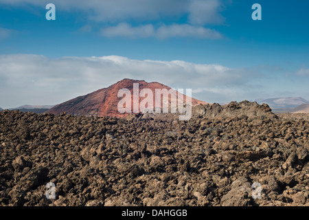 AA campo di lava dalle storiche eruzioni di Lanzarote con Montana Bermeja, un giovane, ossidato, rosso, stromboliano cono vulcanico sullo sfondo Foto Stock